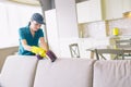 A picture of girl cleaning edge of sofa. She uses small vacuum cleaner. Woman is professional. She does work perfectly.