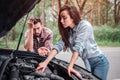 A picture of girl trying to fix detail in car. She is leaning on car and looking to all detailes that are under hood Royalty Free Stock Photo