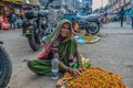 T Stock photo of 60 to 70 aged Indian grandma or old women wearing saree , selling jujube fruitit on the street of city market .