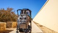 Picture of a gray baby carriage standing outdoors near the wall