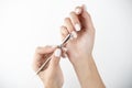 Picture of hands using cuticle pusher while doing manicure on isolated while background