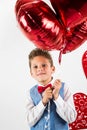 Saint Valentine`s day. Handsome gentleman boy with blue vest, red tie, red roses bucket and red balloons . Valentines day kids. L