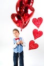 Saint Valentine`s day. Handsome gentleman boy with blue vest, red tie, red roses bucket and red balloons . Valentines day kids. L