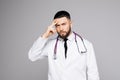 Picture of a handsome young doctor thinking about treatment or something on gray background Royalty Free Stock Photo