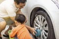 Happy child being a little helper by helping her daddy cleaning up the car.