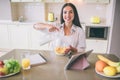 A picture of happy girl sitting at table and pouring milk into bowl with corn flakes. She smiles on camera. There is Royalty Free Stock Photo