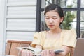 A picture of a happy woman sitting at a coffee shop, an Asian woman analyzing work in a coffee shop and working on a laptop