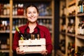 Picture of happy woman with wooden box with bottles in her hands in wine shop