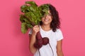 Picture of happy young gardener girl dresses white casual t shirt, holding beetroot harvest in hands, covering half of her face Royalty Free Stock Photo