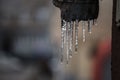 Icicles forming ice stalactites falling fron the edge of the eaves of gutters with droplets dripping in a residential building Royalty Free Stock Photo