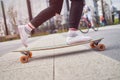 Picture of legs of woman in black jeans riding skateboard on street in city Royalty Free Stock Photo