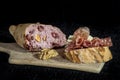 Loaf of French sourdough, called also Pain de campagne, stuffed with meat and walnuts on a black background with a slice of bread