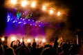 Picture of a lot of people enjoying night perfomance, large unrecognizable crowd dancing with raised up hands and mobile phones on Royalty Free Stock Photo