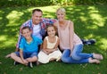 The picture of love and happiness. A portrait of a happy family sitting on the grass together on a sunny day. Royalty Free Stock Photo