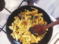 Picture of macaroni dish in cast iron pot and wooden spatule being seared with gas torch, driiping pan with pasta on white gas