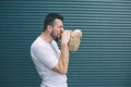 A picture of man blowing paper bag. He feels bad. Guy is going to vomit. Isolated on striped and blue background.