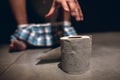 Picture of man`s hand reaching to paper roll after defecation. Guy sit on pot in rest room with pants on his feet. Alone