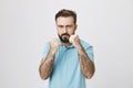 Picture of mature man holding his fists up ready to fight while standing near white wall. Person with a beard and