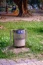 A picture of metallic dustbin in a park beside lake and `use me` written on it