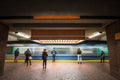 Metro entering fast in a peak transit station with passengers seen from behing standing immobile in front of the speed of train Royalty Free Stock Photo