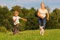 Mother runs with her boy and two small dog on a meadow Royalty Free Stock Photo
