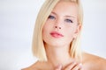 The picture of natural beauty. Poised young woman touching her skin against a white background.