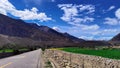 A picture of natural scenery composed of mountains, roads, and fields under blue sky and white clouds.