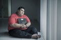 Pensive obese man sits near the window with scale