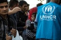 Worker of the UNHCR, the United Nations Agency for refugees, standing in front of a crowd of refugees, including a baby