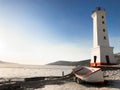 Picture of old lighthouse and wooden boat on the seashore of Magadan, Russia Royalty Free Stock Photo