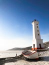 Picture of old lighthouse and wooden boat on the seashore of Magadan, Russia Royalty Free Stock Photo