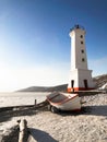 Picture of old lighthouse and wooden boat on the seashore of Magadan, Russia Royalty Free Stock Photo