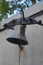 An old rusty iron bell hanging on the wall of the house