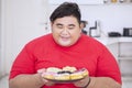 Overweight man looks happy to eat tasty donuts Royalty Free Stock Photo