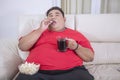 Overweight man eats popcorn and drinks cold cola