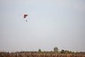 orange and Green parachute, made for two persons, a beginner and an instructor, falling fro the sky during a parachuting skydiving