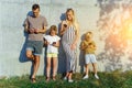 Picture of parents and children with phones in their hands standing on concrete wall on street