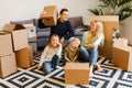 Picture of parents with children sitting on floor among cardboard boxes