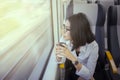 Pensive woman holds coffee in airport train