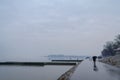 People walking with umbrellas near the Danube river during a heavily foggy and rainy winter afternoon in Zemun, Belgrade, Serbia