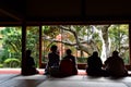 A picture of people siting by the edge of a Japanese style guest room and admiring the beautiful autumn colors of the garden.