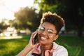 Woman sitting outdoors in park talking by mobile phone