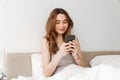 Picture of pleased woman with natural beauty lying in bed with w