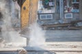 Jackhammer mounted on a renovation vehicle, with a pneumatic drill perforating the asphalt of an urban road being renovated