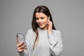 Picture of pretty young woman listening music with earphones dressed in sweater using mobile phone isolated over grey wall Royalty Free Stock Photo