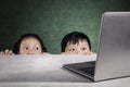 Primary students hiding behind white table Royalty Free Stock Photo