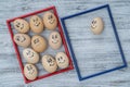 Picture red and blue frame and many funny eggs smiling on wooden wall background, closeup. Eggs family emotion face portrait.