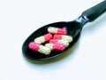 A picture of red and white capsules on a black spoon , Royalty Free Stock Photo