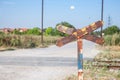 Level crossing sign, called crossbuck, saltire or Saint Andrews cross, rusted, standing on a countryside road which crosses Royalty Free Stock Photo