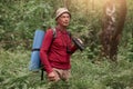 Picture of senior man looking aside attentively, wandering in forest, enjoying beautiful nature, having backpack and sleeping pad Royalty Free Stock Photo